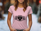 A person in a pink Garment Graphics T-shirt featuring a black Scania Power logo with stylized eagle heads stands in front of a blurred outdoor background with trees.