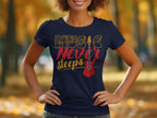 A person stands outdoors, hands on hips, wearing Garment Graphics’ unique navy T-shirt with Music Never Sleeps in bold letters and a striking red electric guitar design. Blurred autumn trees provide the perfect backdrop for this standout guitar T-shirt.