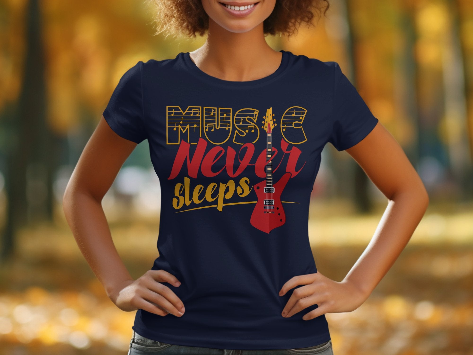 A person stands outdoors, hands on hips, wearing Garment Graphics’ unique navy T-shirt with Music Never Sleeps in bold letters and a striking red electric guitar design. Blurred autumn trees provide the perfect backdrop for this standout guitar T-shirt.