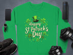 A festive Garment Graphics green shirt with Happy St Patricks Day, featuring a leprechaun hat and shamrocks, is displayed with a smartphone, smartwatch, sneakers, dumbbells, wireless speaker, and headphones on a gray surface.