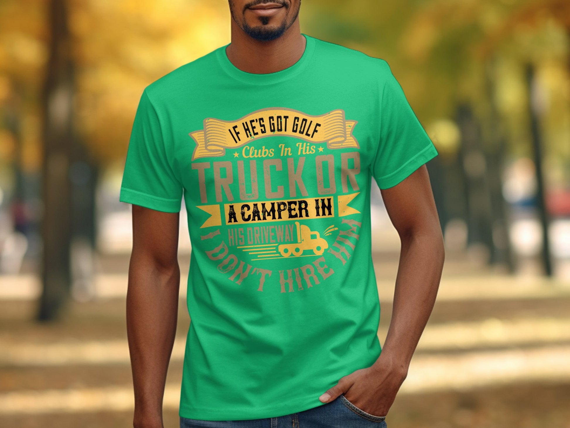 A man in a Garment Graphics green T-shirt with the funny quote If hes got golf clubs in his truck or a camper in his driveway, dont hire him. stands amid trees with fall leaves, setting the perfect backdrop for this humorous moment.