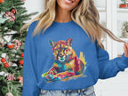 A woman with long, light hair stands by a decorated Christmas tree, wearing Garment Graphics blue unisex sweatshirt featuring a vibrant big cat design. She holds a hair strand with her left hand, with white shelves in the background.