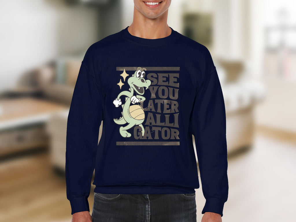 A person models a navy sweatshirt from Garment Graphics, showcasing a playful alligator holding a basketball with the text See you later alligator, set against a softly blurred living room background.