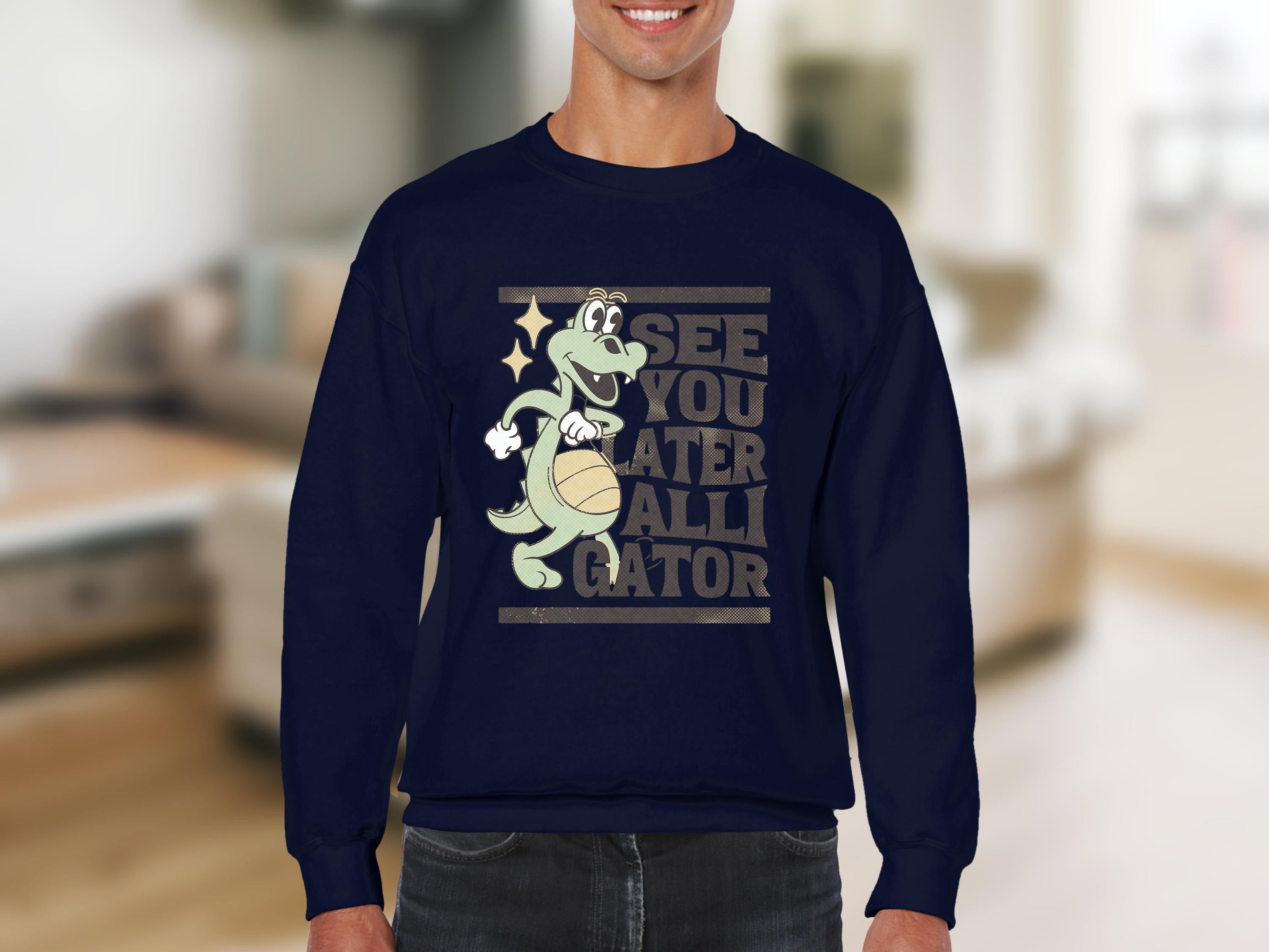 A person models a navy sweatshirt from Garment Graphics, showcasing a playful alligator holding a basketball with the text See you later alligator, set against a softly blurred living room background.