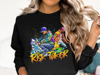 A person with long, wavy hair sports a black Garment Graphics sweatshirt featuring a vibrant graphic of two casually dressed figures. The bold graffiti-style text RISK TAKER Street Dance captures the dynamic spirit of street dance finals.
