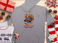 Garment Graphics gray hoodie features a cartoon turkey sprinting with TURKEY ON THE RUN on the front, surrounded by gifts, red berries, and cozy details—making it a funny hoodie perfect for holiday cheer.