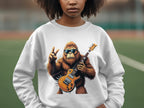 A person is wearing a Garment Graphics sweatshirt with a gorilla holding an electric guitar and flashing a peace sign, complete with sunglasses, set against an outdoor sports field.
