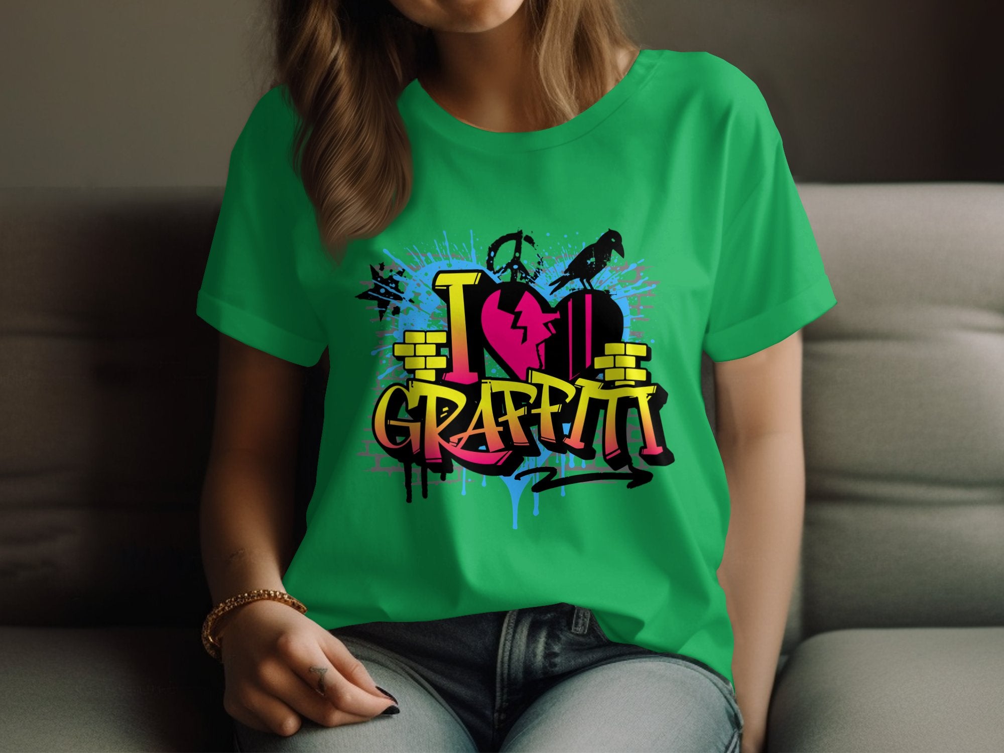 Wearing a Garment Graphics green T-shirt featuring bold urban designs with the phrase I love graffiti, a person relaxes on the couch, their hands resting casually on their lap. The shirt showcases a red heart and paint splatters, enhancing the street art-inspired look.