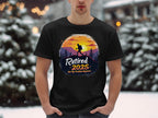 Sporting a Garment Graphics black t-shirt, a vibrant hiker graphic and Retired 2025 - Not My Problem Anymore text shine against a sunset with snow-covered trees, creating the perfect retirement scene.