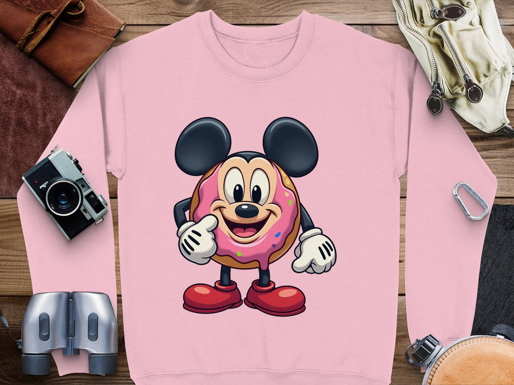 Garment Graphics presents a pink unisex sweatshirt featuring a joyful donut character with large ears and gloves, sprinkled with colors. Ideal for travel lovers, its adorned with cameras, binoculars, and adventure essentials.