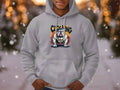 A person wears a classic fit Gray Graphic Bulldog Design Hoodie by Garment Graphics, ideal for casual style. It features Chilling with softly blurred bokeh lights and snowflakes in the background.