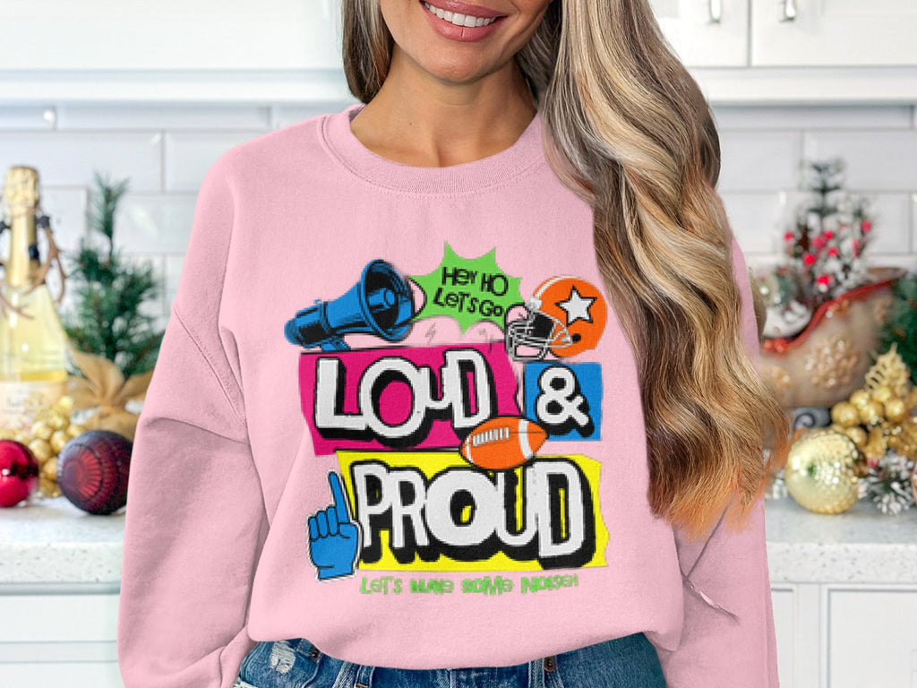 In a festive, holiday-themed kitchen, someone showcases their unique style in a Garment Graphics pink sweatshirt with vibrant graphics and bold text: Hey Ho Lets Go Loud & Proud, Lets Make Some Noise, from the unisex Loud and Proud Sweatshirts collection.