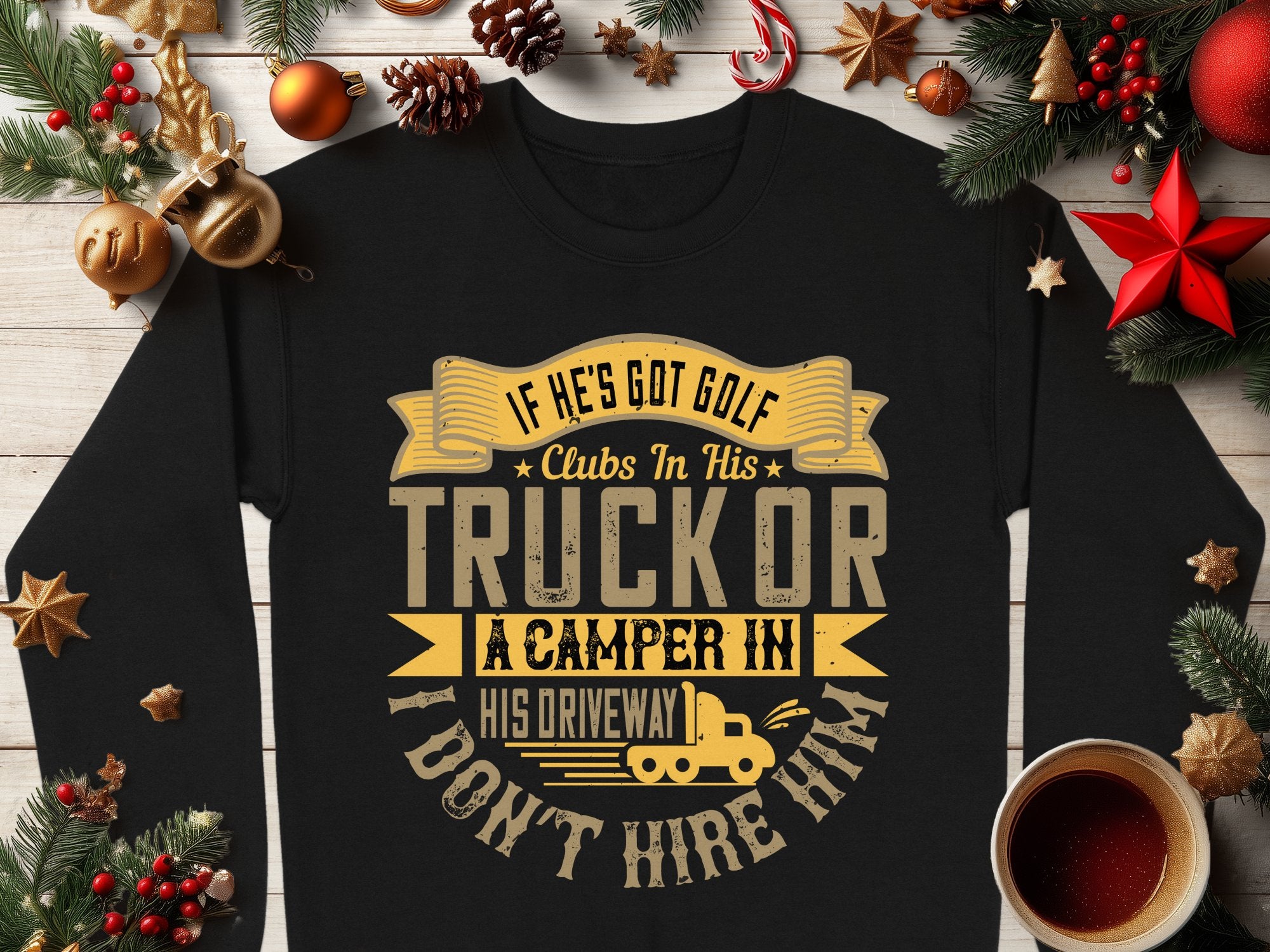 Garment Graphics presents a black, humorous sweatshirt with the text If hes got golf clubs in his truck or a camper in his driveway, I dont hire him in yellow and white. Perfect for casual wear with a playful twist, its styled amidst festive decorations, pinecones, and coffee on wood.