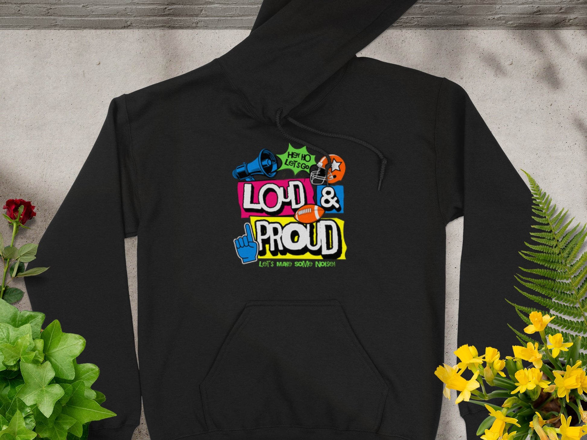 Garment Graphics Lets Make Some Noise Hoodies showcase a black hoodie with a colorful graphic of a microphone, ear with sound waves, and peace sign. The text says HEY YOU, LETS GO LOUD & PROUD, with vibrant red and yellow flowers on the gray background.