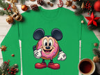 Garment Graphics quirky green sweatshirt features a large-eared cartoon character posing confidently. It is playfully designed with festive pine branches, red stars, baubles, and a cozy coffee cup on a wooden surface.