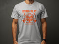 Someone is wearing a light gray Garment Graphics football T-shirt with bright orange text: BORN TO PLAY and YOUNG SQUAD FOOTBALL, featuring a soccer ball design and the inspiring motto One Goal One Dream: KICK. SCORE. CELEBRATE.