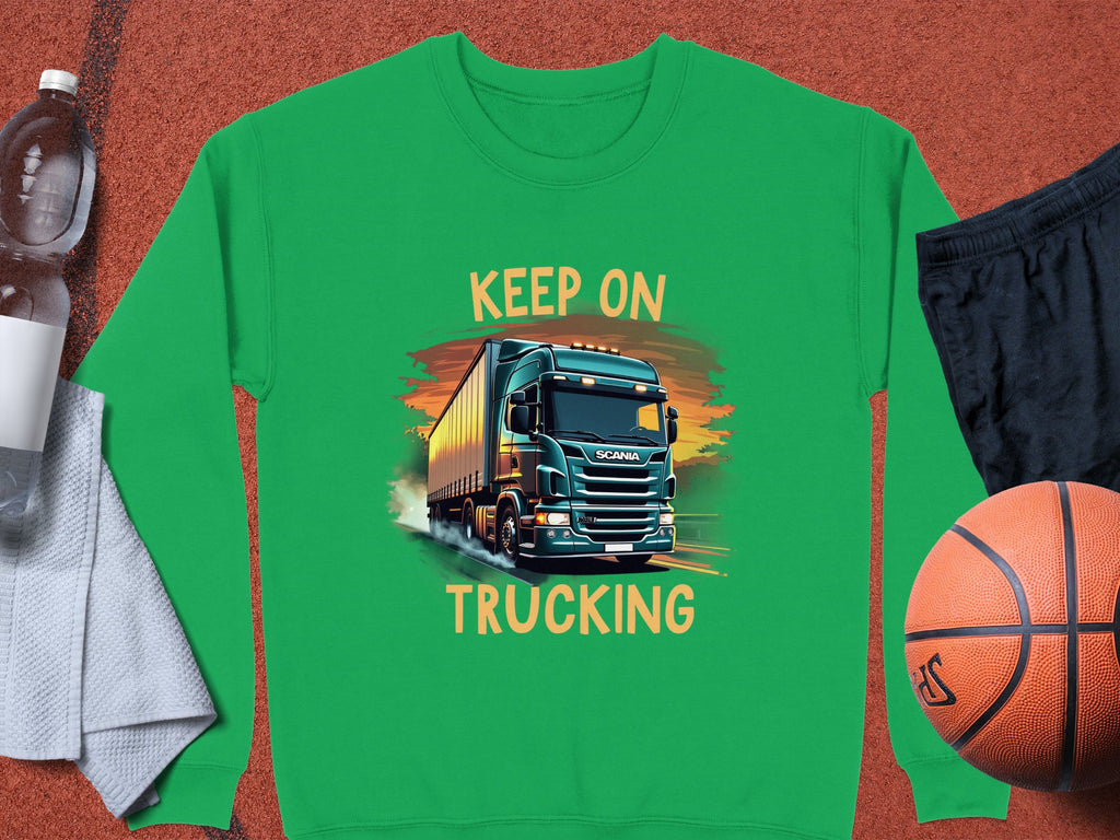 A Garment Graphics green graphic sweatshirt with Keep On Trucking truck design is on a surface beside a basketball, black shorts, a white towel, and a water bottle.
