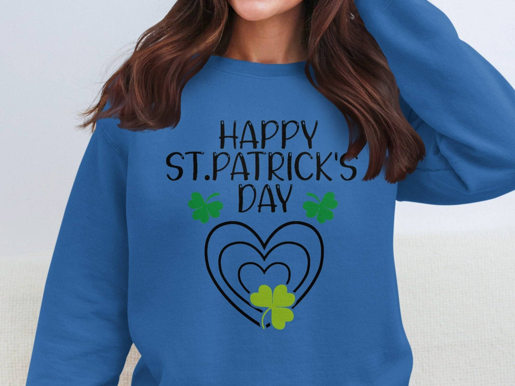 Someone is wearing a Garment Graphics festive sweatshirt with Happy St. Patricks Day, showcasing three green shamrocks and heart patterns, while their long brown hair obscures their face against the blue fabric.