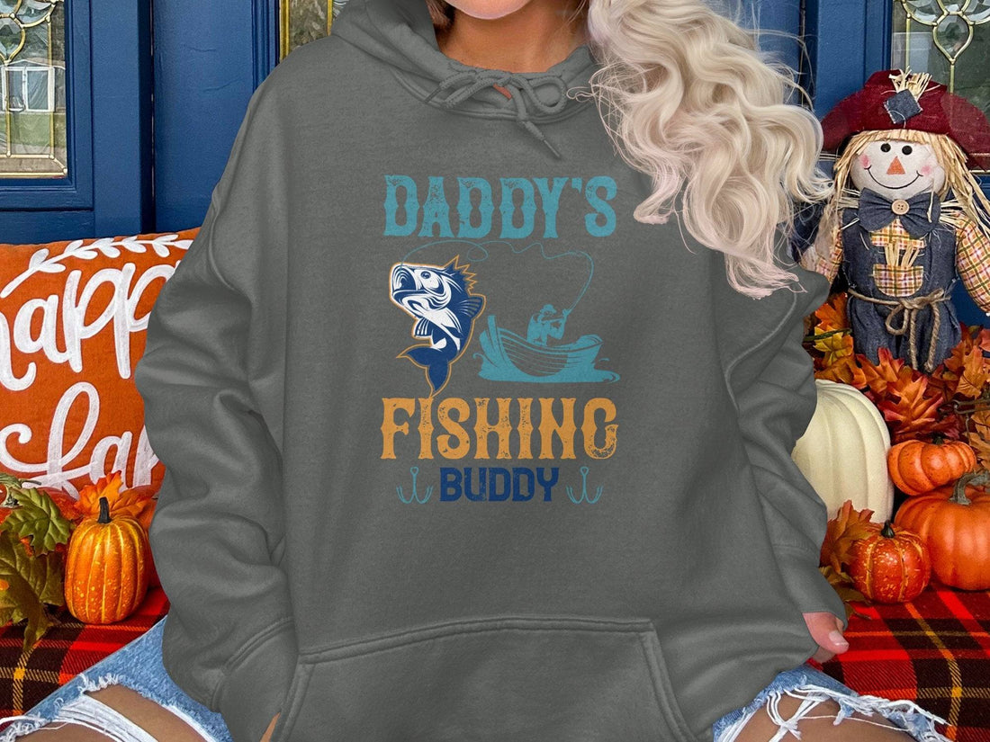 Someone wearing a Garment Graphics black graphic hoodie featuring Daddys Fishing Buddy with a fish and boat design stands with hands in pockets, ready for outdoor adventures.