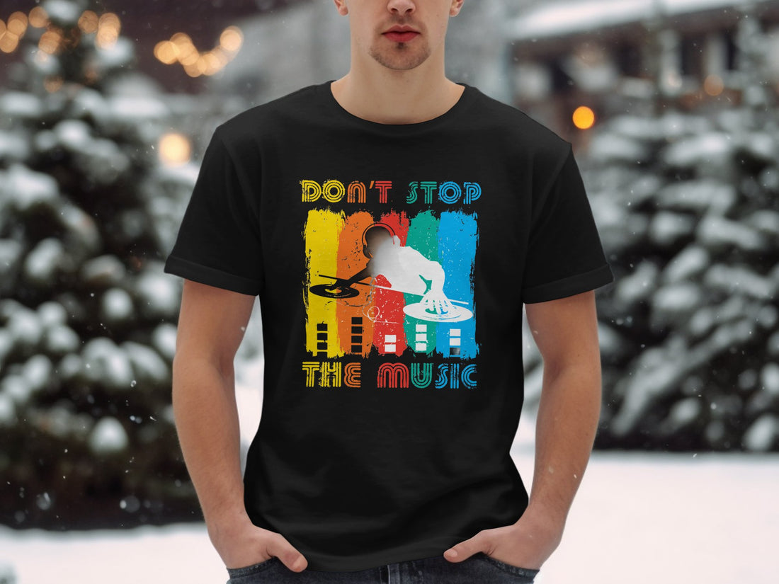 A man wearing a Garment Graphics white t-shirt featuring a vibrant DJ graphic and the phrase Dont Stop the Music stands in a grassy area, attracting music lovers attention.