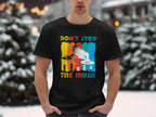 Amid snowy scenery with snow-laden trees, someone stands dressed like a music aficionado in a Garment Graphics black T-shirt. The shirt features a vibrant DJ graphic and the words Dont Stop the Music, embodying the essence of party-goers everywhere.