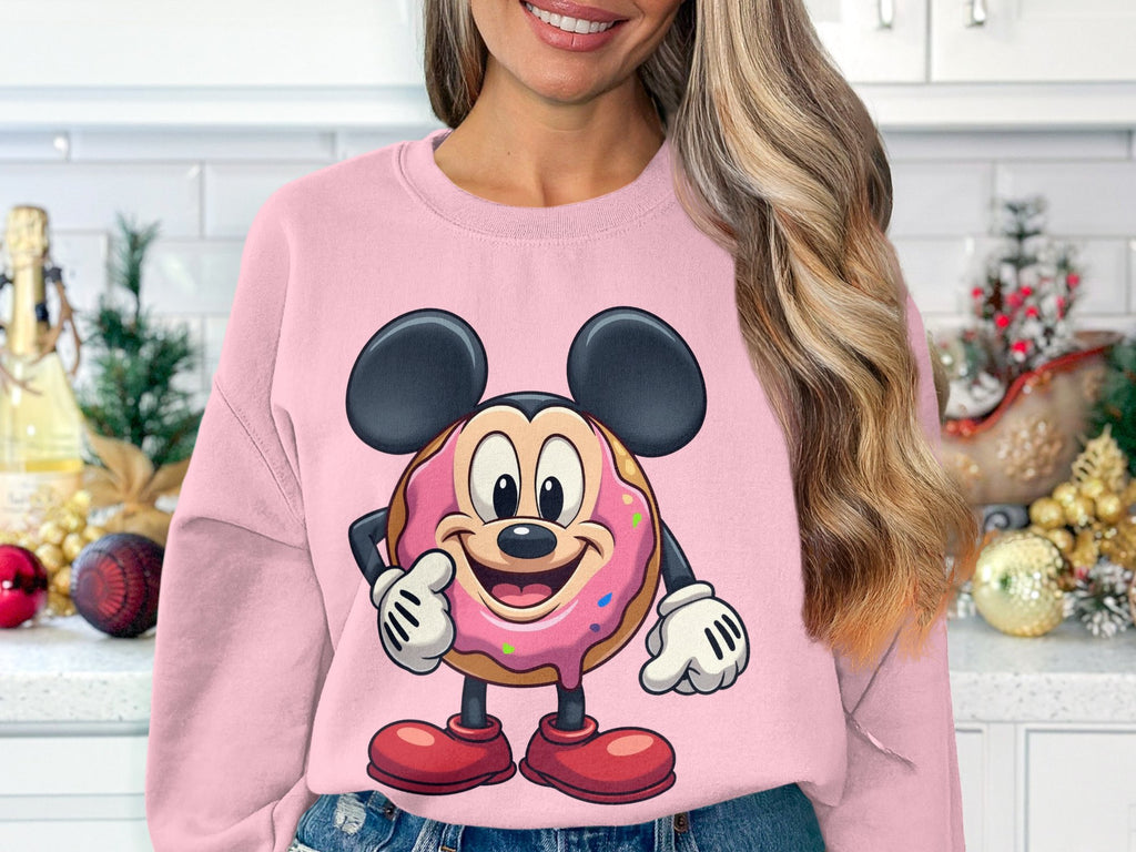 Someone in a pink unisex sweatshirt by Garment Graphics, adorned with a playful donut-mouse graphic, is standing in a kitchen adorned with holiday decor and pine branches.