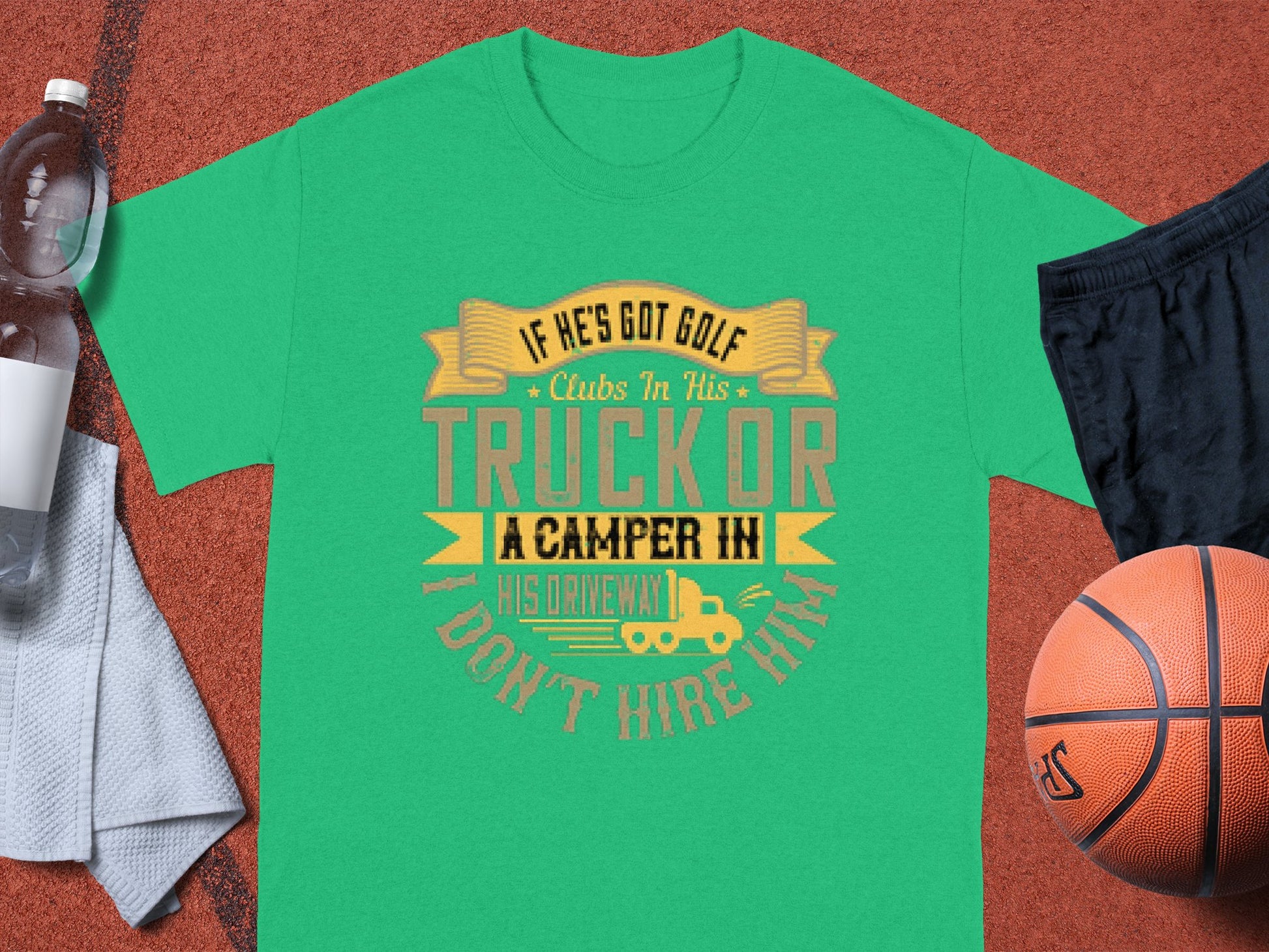 A green Garment Graphics t-shirt says: If hes got golf clubs in his truck or a camper in his driveway, I dont hire him. Perfect for camping humor fans, its artistically displayed on a brown textured background with a water bottle, shorts, towel, and basketball nearby.