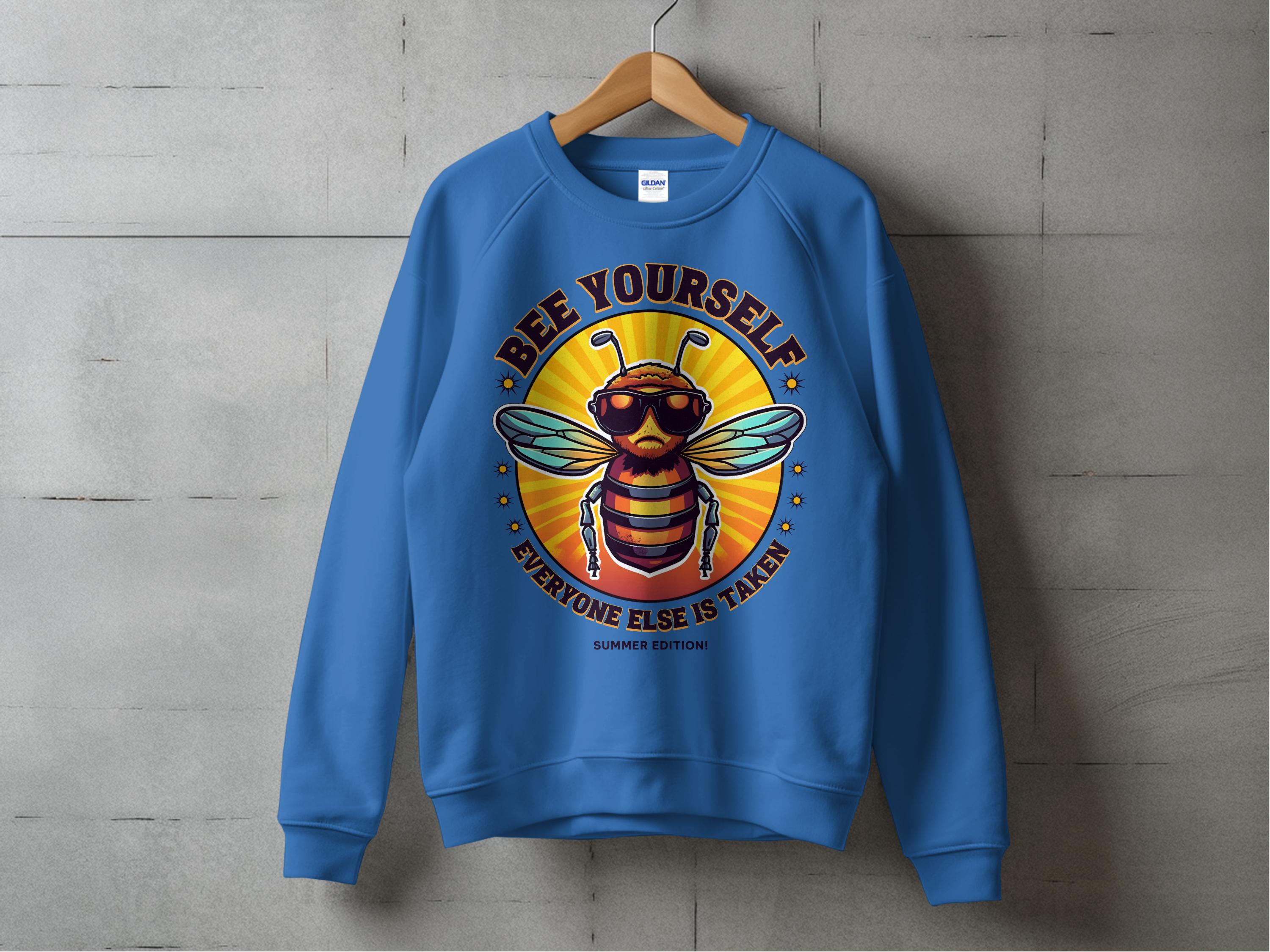 Garment Graphics Summer Edition sweatshirt features a cartoon bee wearing sunglasses in a bright yellow circle, with the phrase BEE YOURSELF EVERYONE ELSE IS TAKEN on the front. It comes in unisex sizing for a perfect fit for everyone.