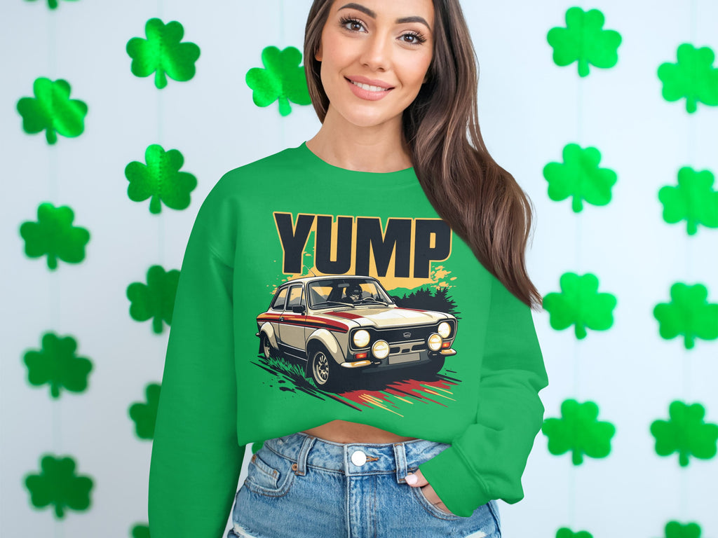 A person is wearing a Garment Graphics green sweatshirt with a YUMP rally car design, standing in front of a wall decorated with shamrocks, perfectly matching the sweatshirts color and theme.