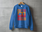 Displayed on the wall is Garment Graphics blue sweatshirt, ideal for music lovers. It showcases silhouettes with musical elements and states Born to be a Musician in vibrant orange and yellow. Available in unisex sizing, its perfect for all aspiring artists.