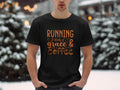 Amid a snowy landscape, a person stands confidently in a black Garment Graphics t-shirt adorned with the inspirational phrase Running on grace & coffee, with snow-covered trees providing a serene backdrop that beautifully blends style and sentiment.