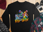 The Garment Graphics black sweatshirt features a vibrant illustration of two dancers in colorful streetwear with Risk Taker Street Dance and Street Dance Wild Free. It’s styled with winter accessories like hats, gloves, and flannel shirts on wood, ideal for the upcoming street dance finals.