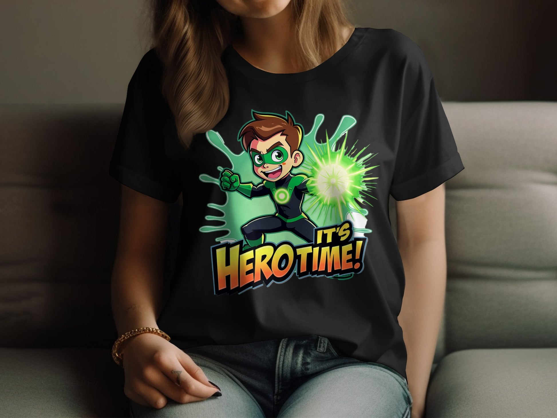 A person lounges on a couch in a Garment Graphics black T-shirt with a green superhero design featuring a cartoon character in a heroic pose, vibrant energy surrounding them, and the phrase Its Hero Time! below, enhancing their colorful wardrobe.