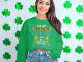 Amidst a backdrop of green shamrocks, someone models Garment Graphics green sweatshirt with the text, Im not addicted to fishing, we are just in a very committed relationship, effortlessly paired with denim shorts in unisex sizing.