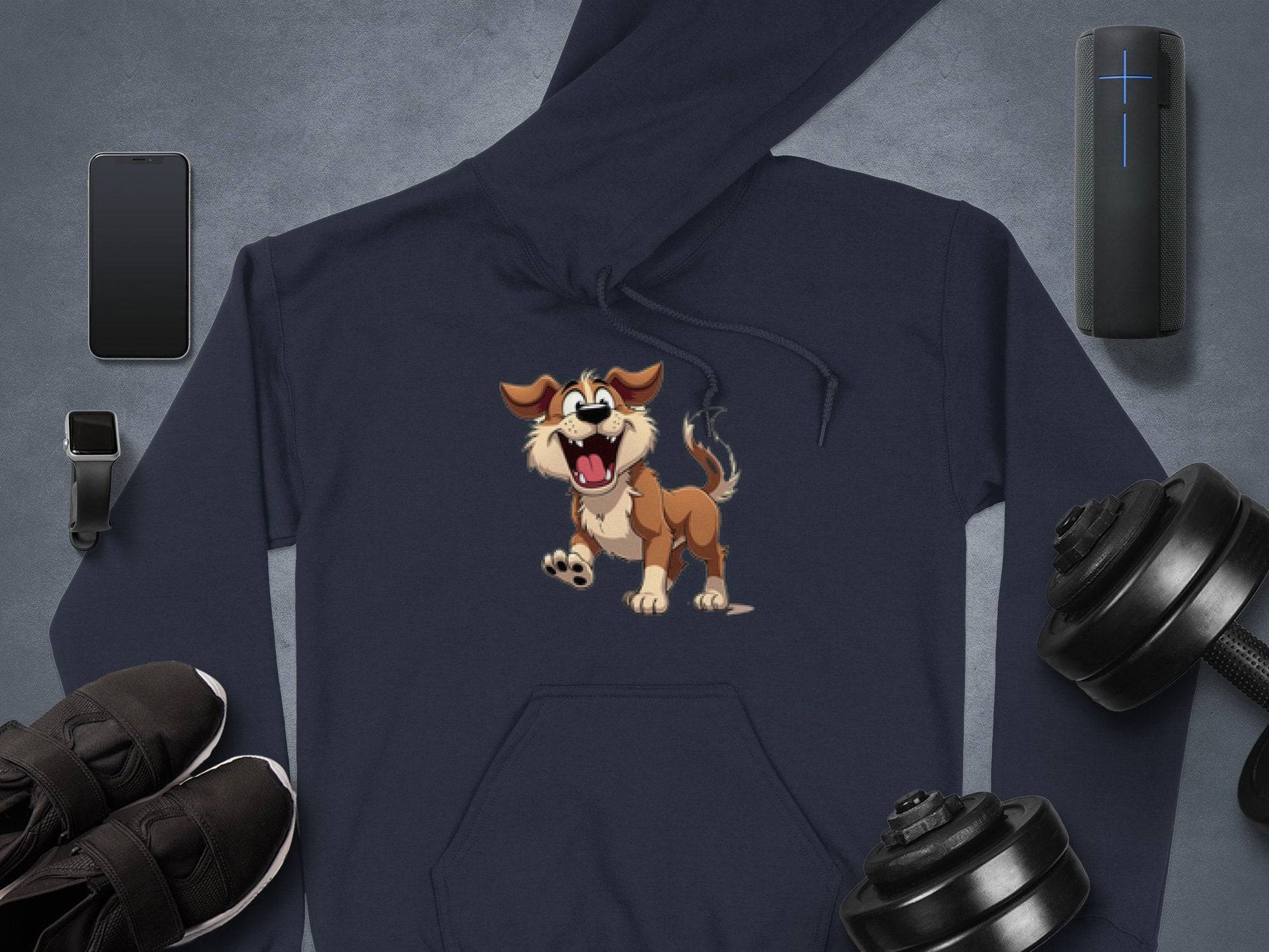 The Garment Graphics dark cartoon puppy hoodie with a playful design is laid flat, surrounded by a smartphone, wireless earbuds in a case, a smartwatch, portable speaker, black sneakers, and adjustable dumbbells on a gray surface. Its perfect for dog lovers seeking style and comfort.