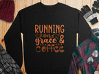 A black Garment Graphics sweatshirt with Running on Grace & Coffee in bold orange rests on wood, paired with a knit hat, gloves, and plaid shirts. Unisex sizing ensures effortless style and comfort.
