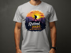 A person wears a Garment Graphics light gray T-shirt with a hiker silhouette against a sunset and trees. Retired 2025 Not My Problem Anymore text captures retirement vibes, set on a dark gray contrast.