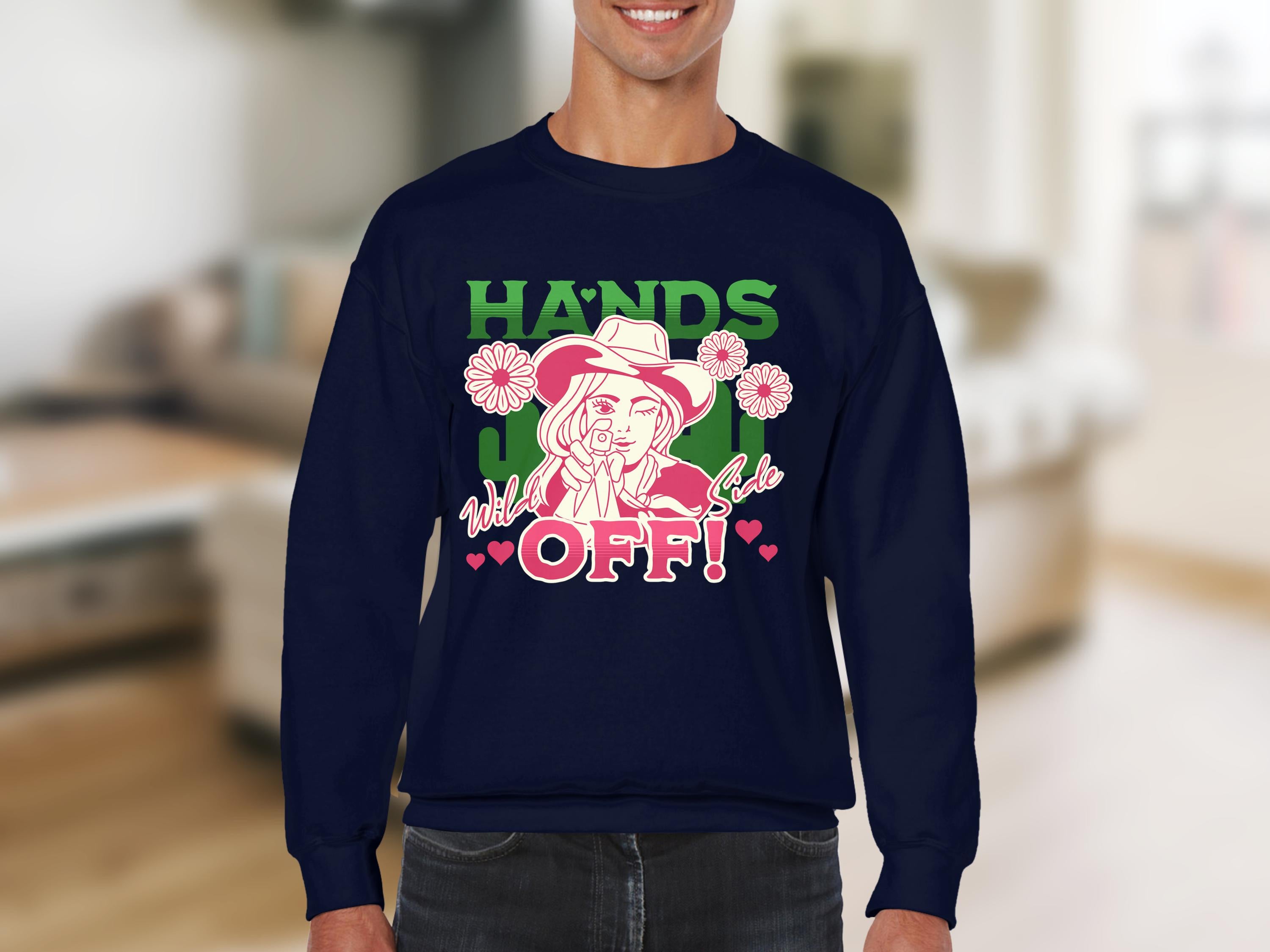 A person wears a navy loose-fit sweatshirt by Garment Graphics, featuring a design of a figure among flowers and text that reads HANDS OFF! and wild girl in pink and green. Perfect for those embracing their wild side with style.