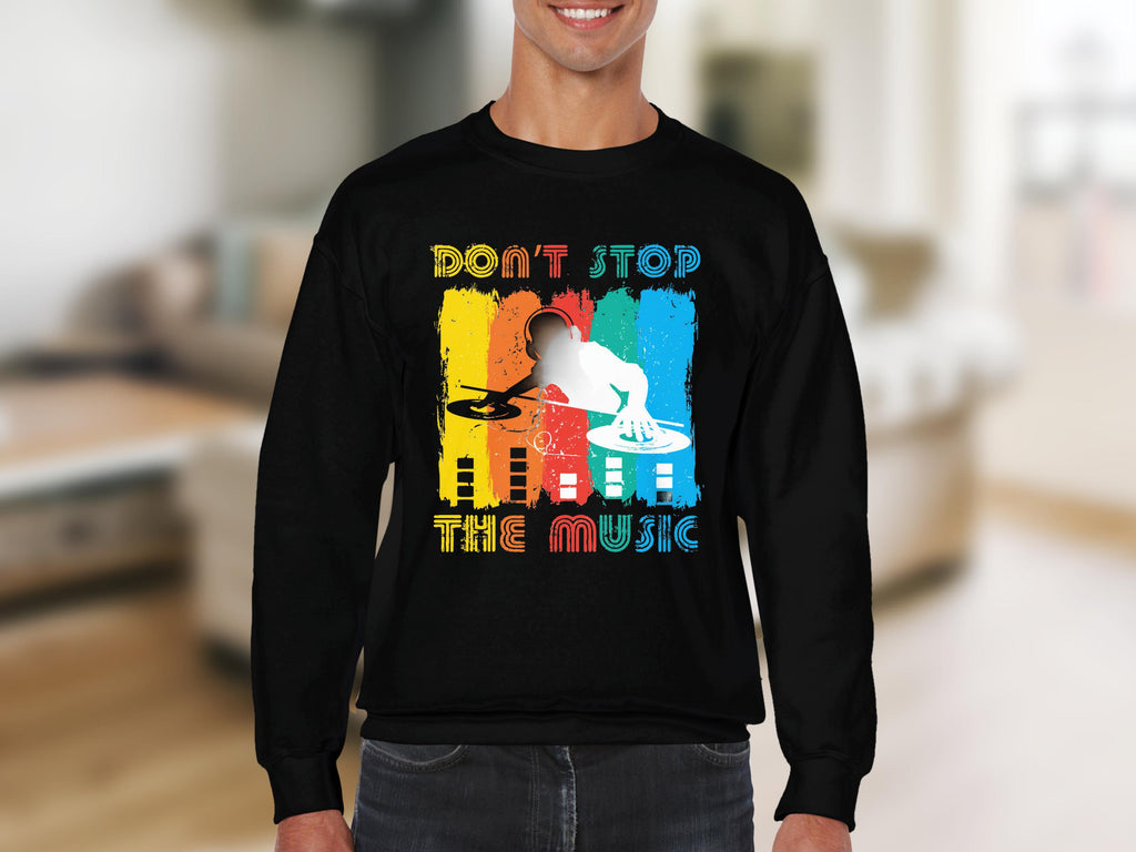A person is wearing Garment Graphics black DJ sweatshirt, adored by music lovers, featuring a colorful design of a DJ silhouette with turntables and vibrant Dont Stop the Music text on a blurred background.