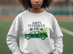 A person proudly wears a Garment Graphics festive sweatshirt showcasing a green truck with shamrocks and Happy St. Patricks Day, standing outdoors, left hand on hip against a blurred background.