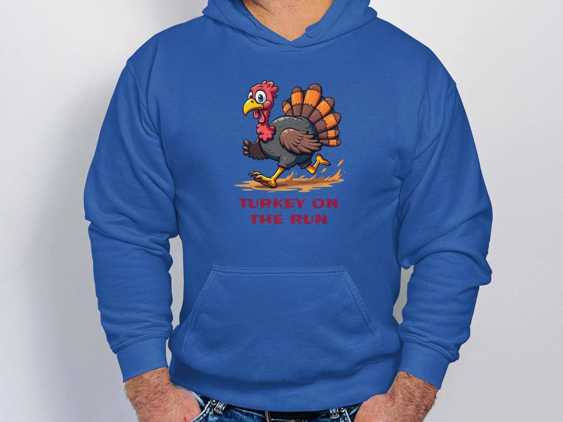 Someone is cozily tucked in a blue Garment Graphics hoodie with a running turkey graphic and the phrase Turkey on the Run. Front pockets make it effortlessly funny, ideal for light-hearted style.