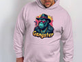 Someone is wearing a medium-heavy fabric Garment Graphics hoodie featuring a chimpanzee with a hat, sunglasses, and chain necklace. The phrase Gangster stands out in colorful letters on the smokey cool gangster gorilla graphic hoodie.