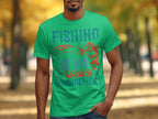 A fishing enthusiast sports a Garment Graphics green t-shirt emblazoned with Fishing Is My Anger Management and decorated with fish hooks and a fish, set against blurry trees in the background.