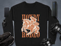 Garment Graphics black print sweatshirt features a design of a person riding a horse with Howdy Rodeo above and below. A speech bubble reads Not Dangerous. With unisex sizing, it pairs perfectly with your phone, smartwatch, or speaker.