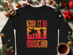 The Garment Graphics black sweatshirt for music lovers features Born to Be Musician with drummer and guitarist silhouettes. Surrounded by festive pine branches and ornaments on wood, a cozy coffee enhances the scene. Available in unisex sizing.
