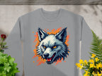 Garment Graphics presents a gray sweatshirt adorned with a fierce wolf graphic, showcasing sharp teeth and striking yellow eyes against an orange splash. Surrounded by green plants and yellow flowers on concrete, its a bold statement piece capturing the wild side.