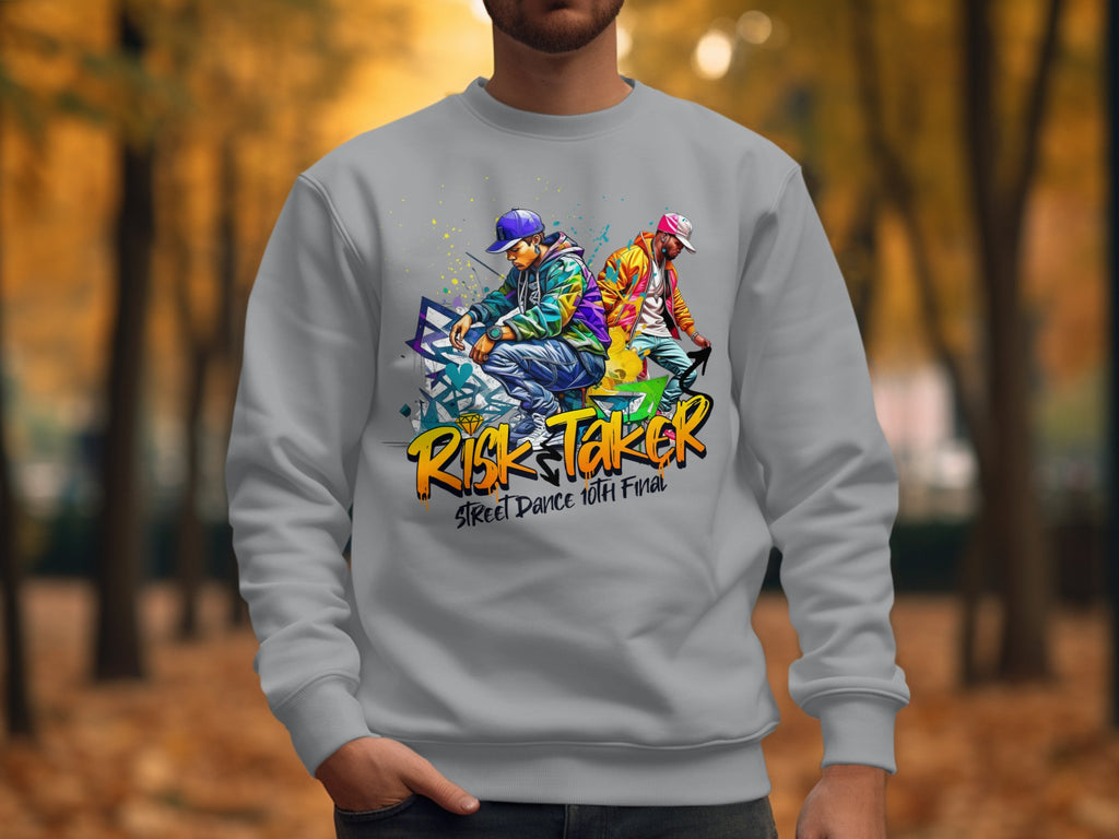 In an autumn park with a blurred background, someone wears a Garment Graphics gray unisex sweatshirt featuring bold street dance graphics of two dancers. The text Risk Taker, Street Dance 10th Final is prominently displayed.