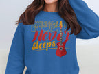 A music enthusiast proudly wears a trendy Garment Graphics sweatshirt adorned with the phrase Music Never Sleeps and an illustration of a red electric guitar.
