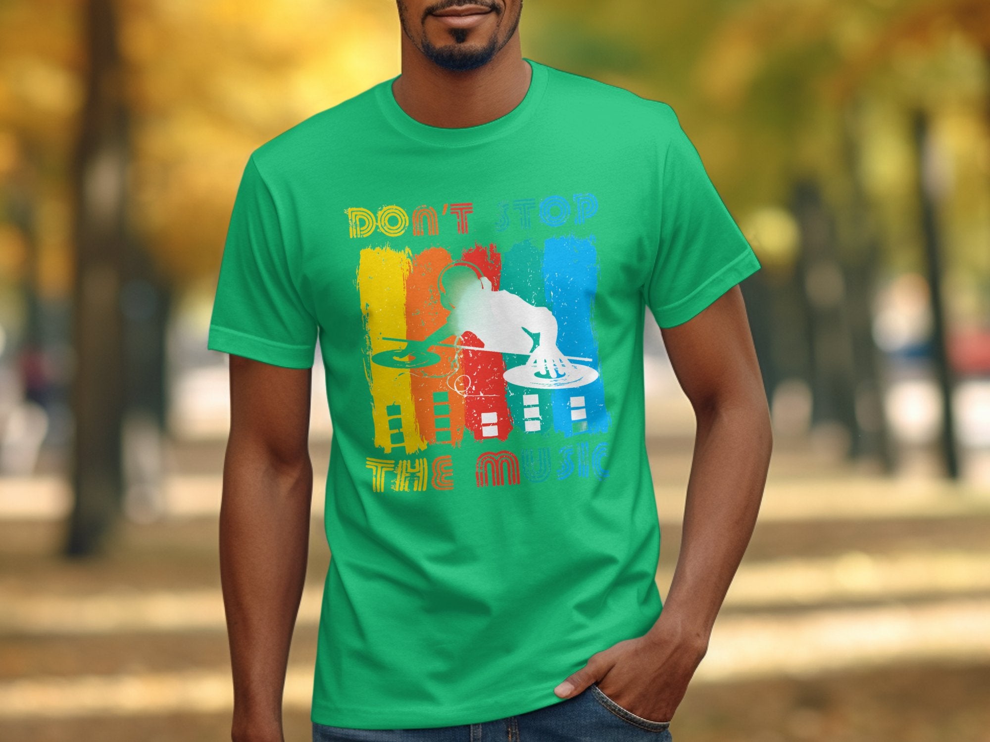 Someone sports a bright green Garment Graphics T-shirt with a colorful DJ graphic and the text Dont Stop the Music. The backdrop features a blurred outdoor scene with autumn leaves.