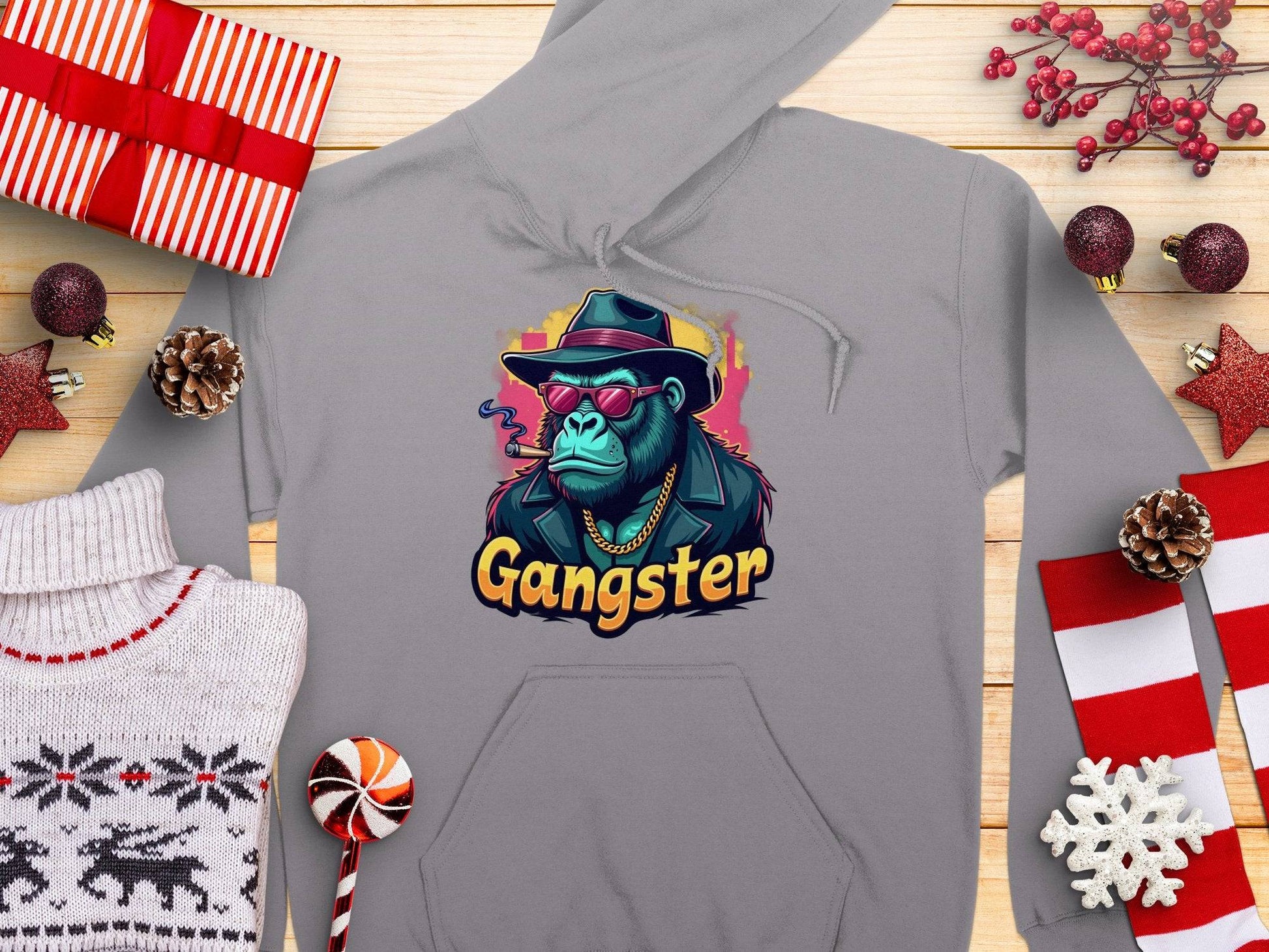 This gray hoodie by Garment Graphics showcases a cool gangster gorilla graphic with a sunglasses-wearing, smoking chimp. Set against Christmas-themed decorations, wrapped gifts, and a knit sweater, this medium-heavy fabric hoodie makes an edgy holiday statement.